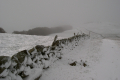 grauer Steinwall im Schneesturm